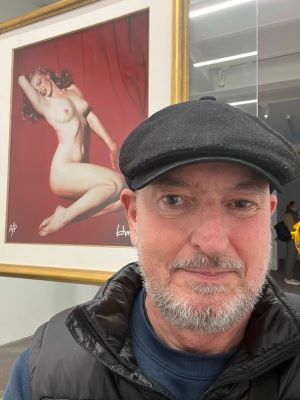 Portrait beside a framed exhibition artwork